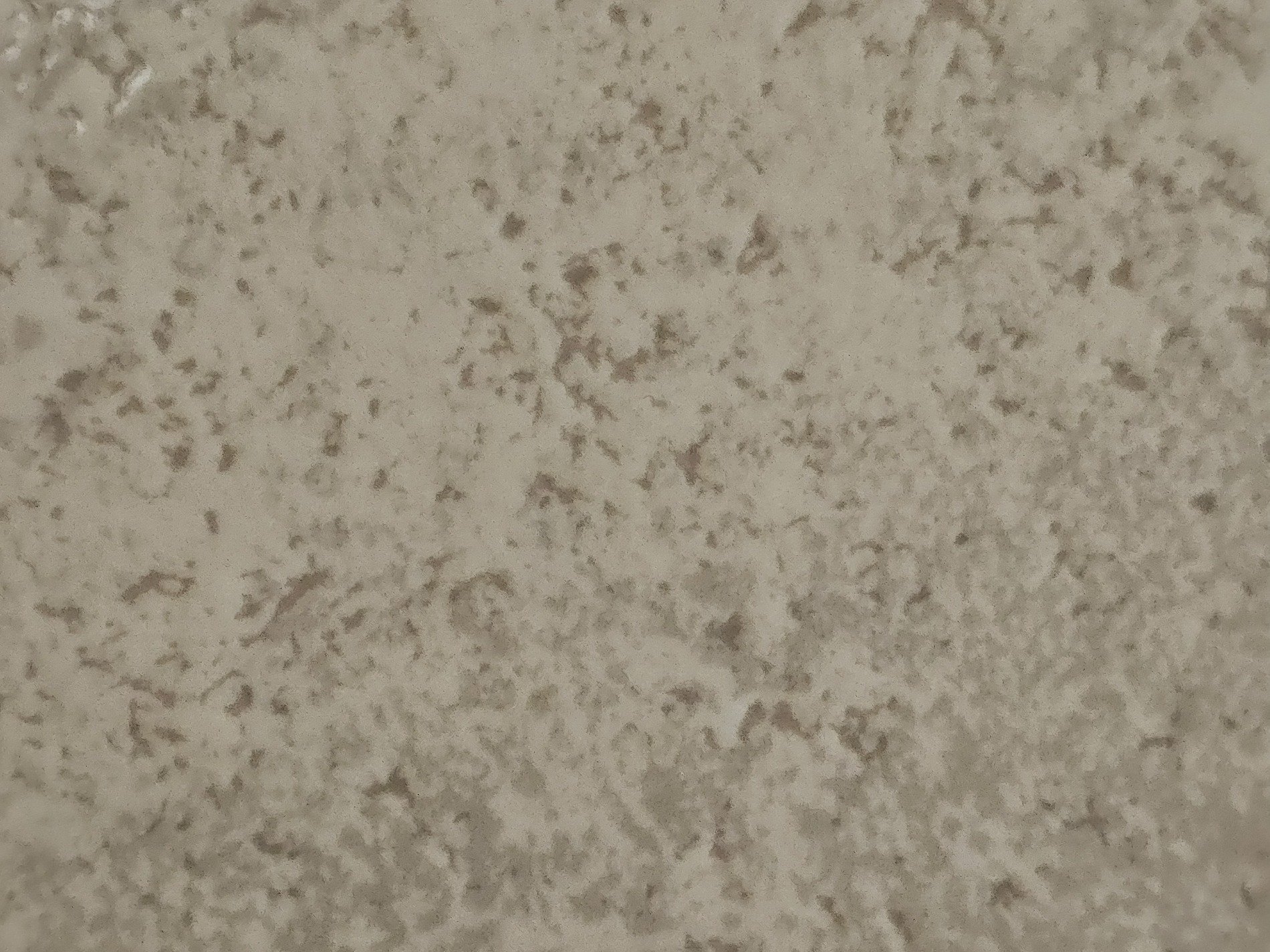 Mottled grey surface, tiny pits in aged concrete, shadows find a home