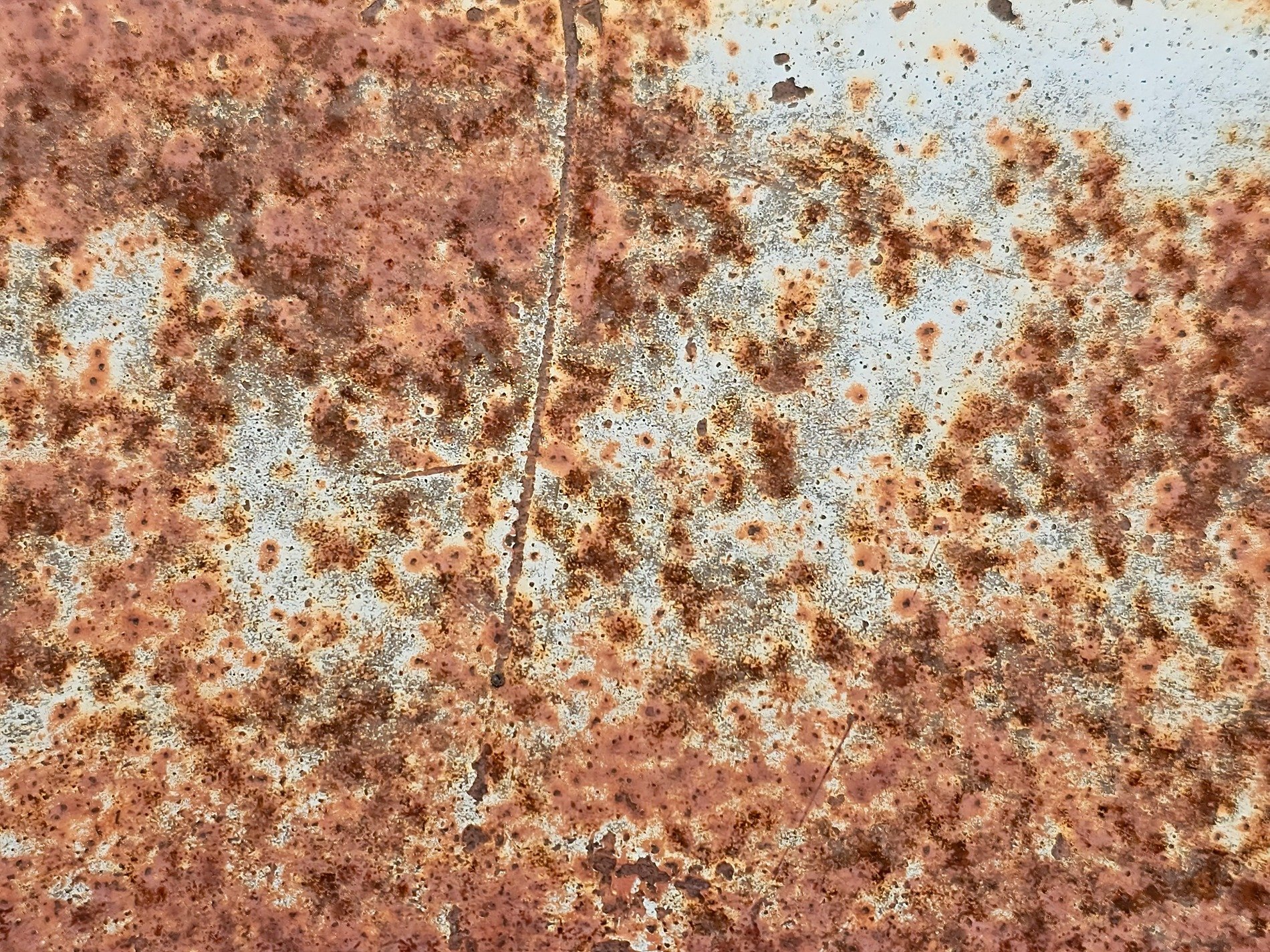 Orange blooms of grit, metal surface starts to fade, iron turns to dust