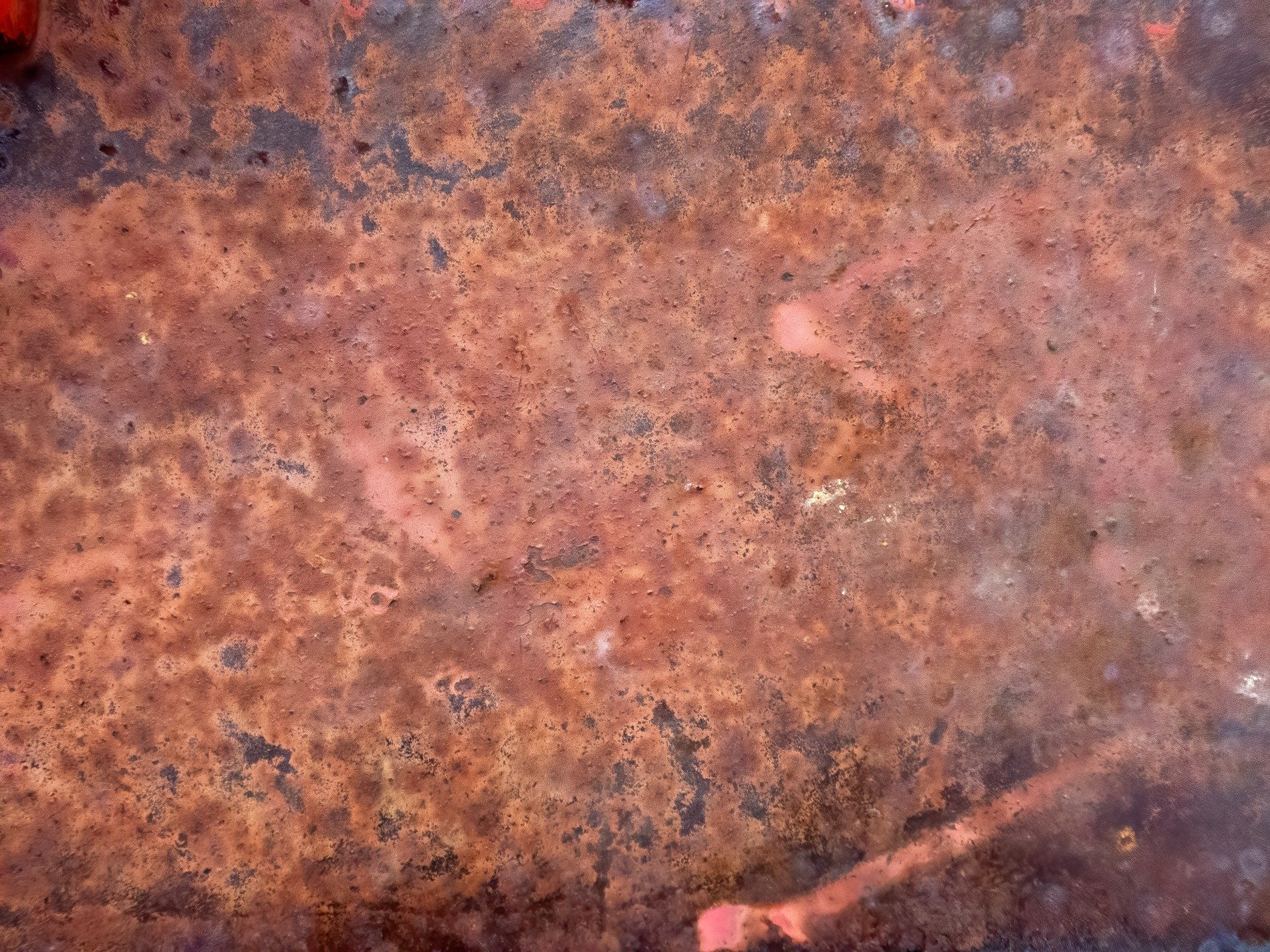 Orange iron flakes, deep brown shadows pool in pits, slow decay of steel