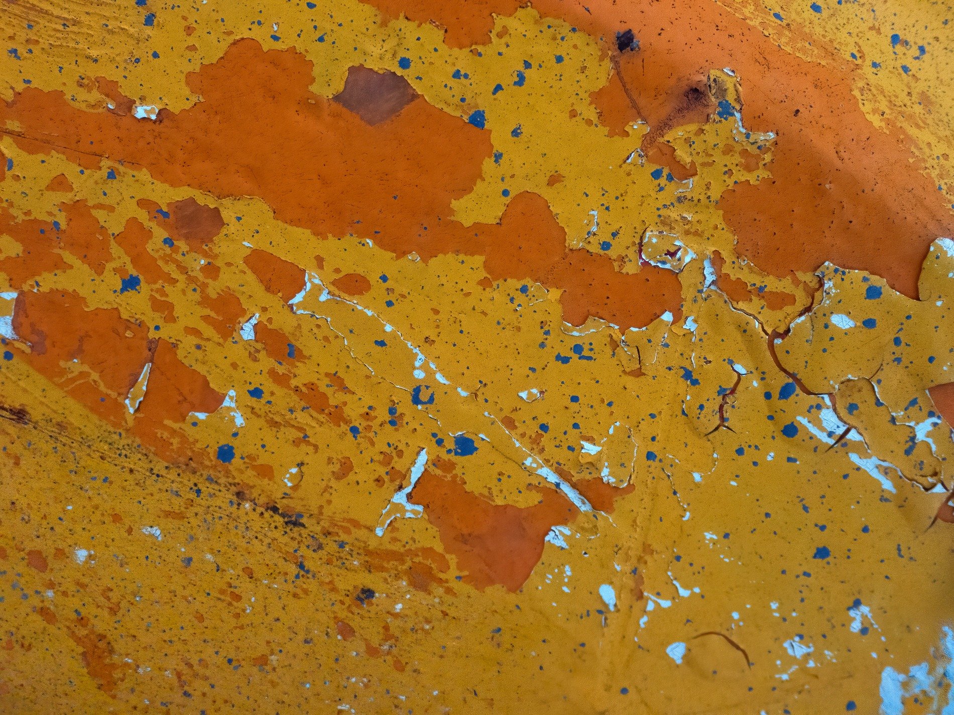 Orange paint flakes fall, yellow layers hide beneath, weather wears the skin