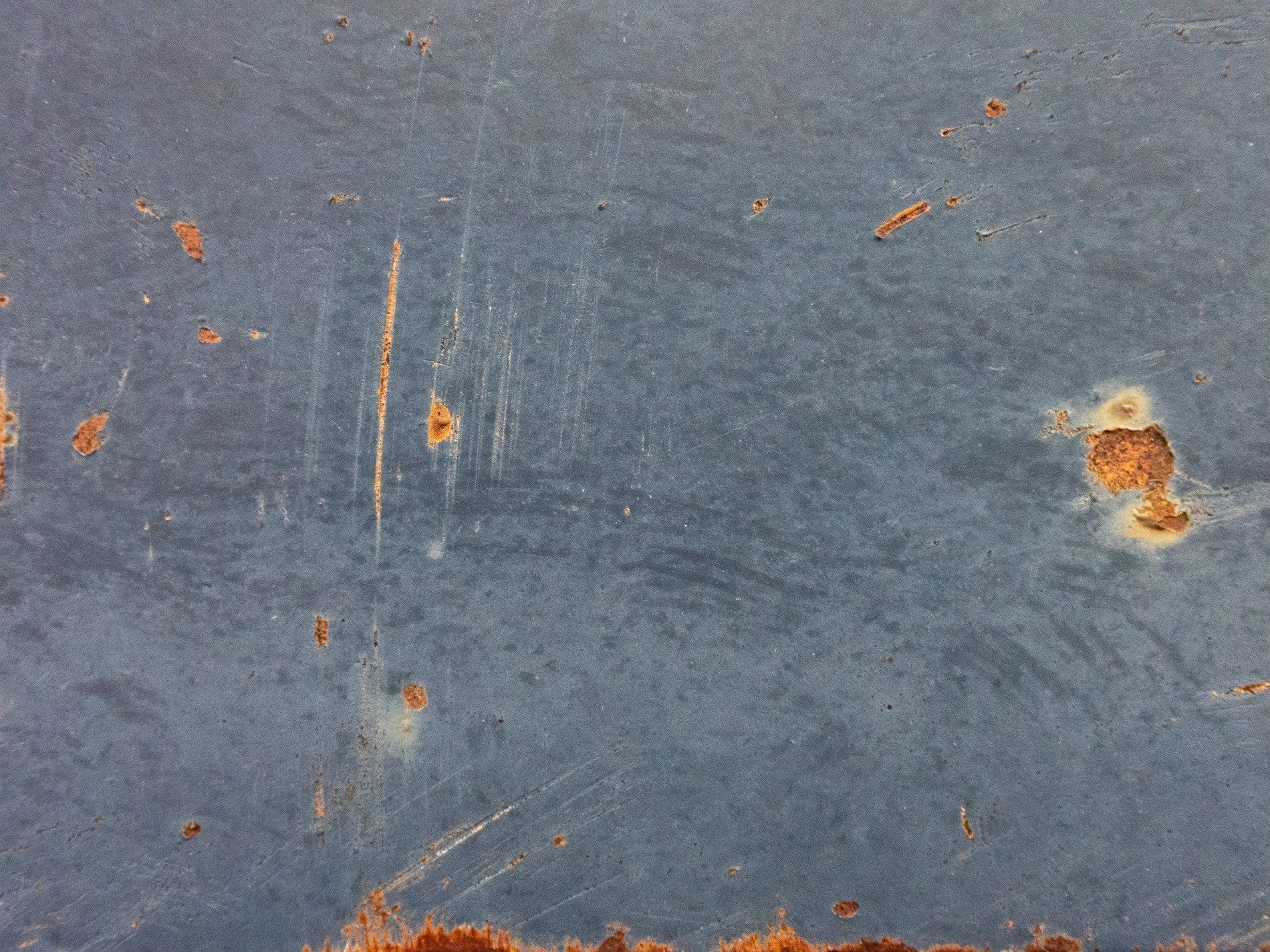 Blue paint wears away, orange rust breaks through the skin, scratches mark the steel