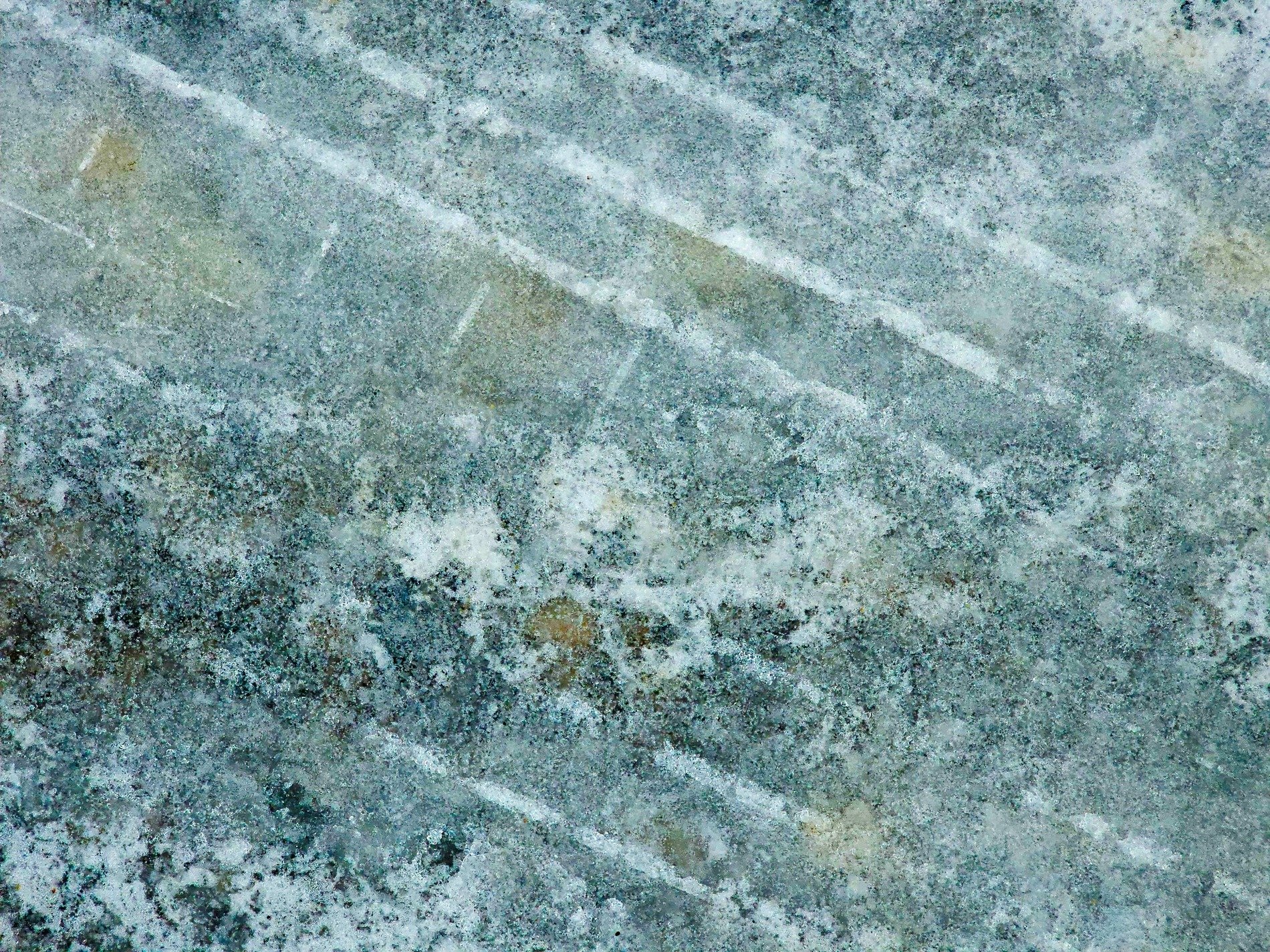 Pale lines mark the stone, frost clings to the textured grain, winter's cold embrace