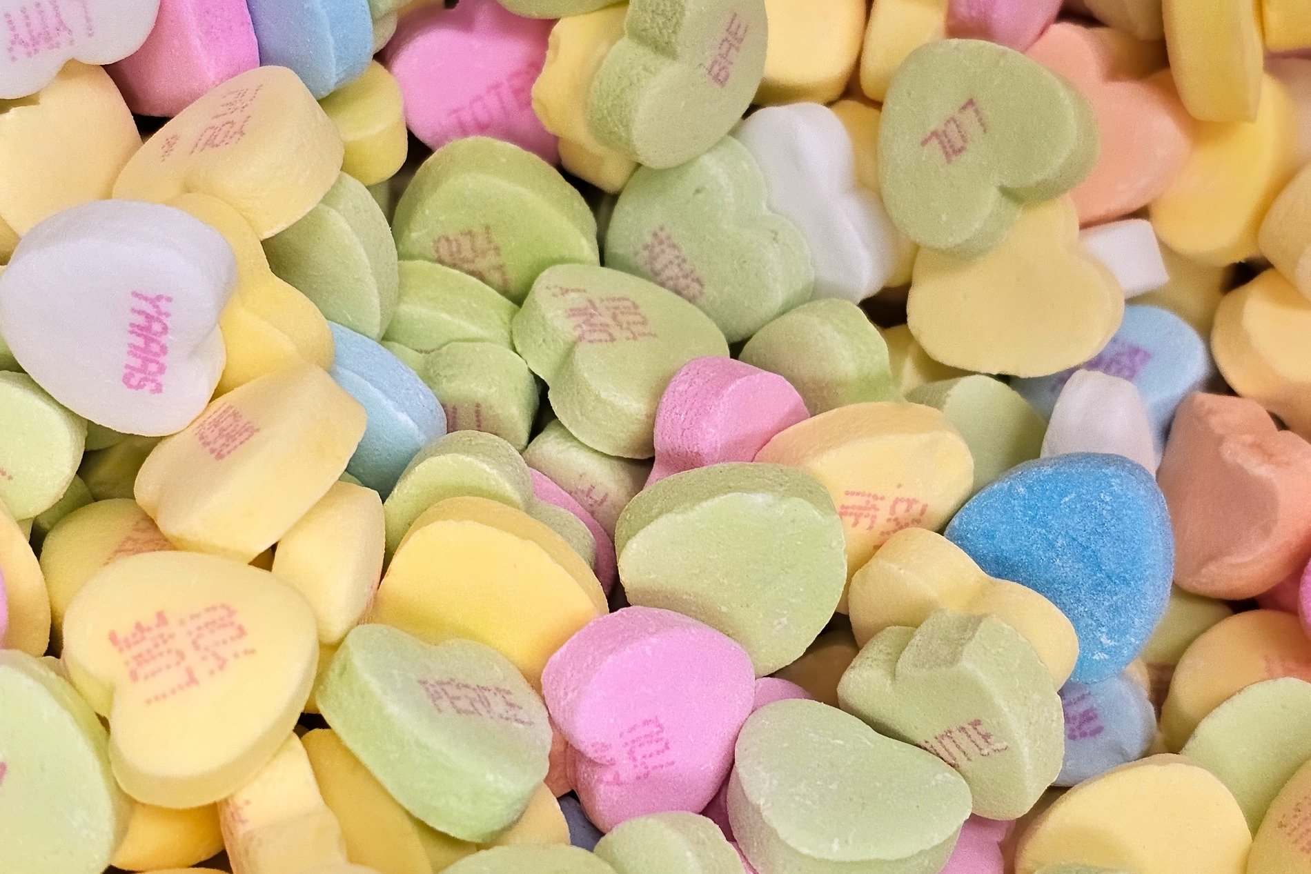 Pastel sugar hearts, sweet words stamped in dusty red, candy love is shared