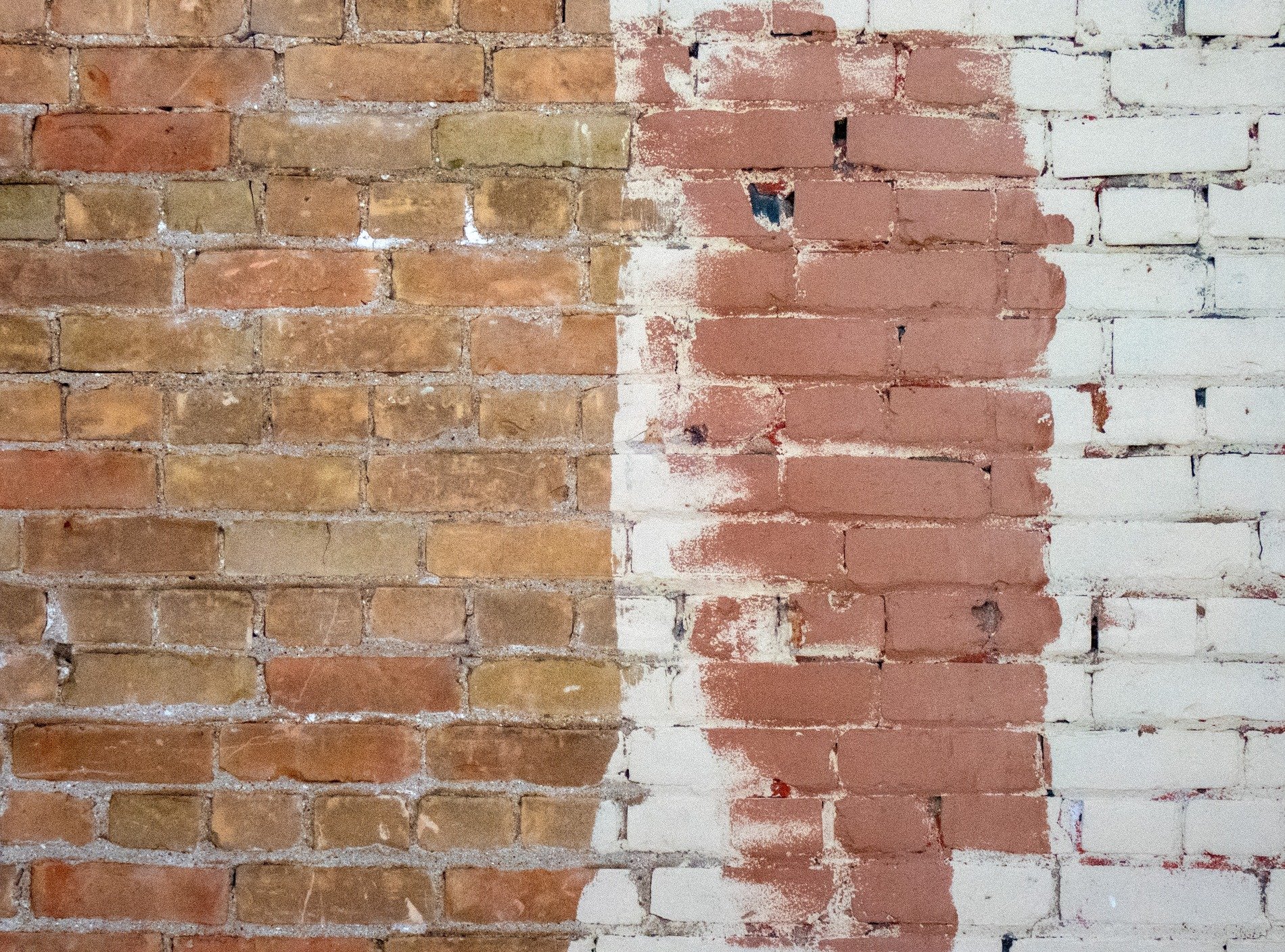 Red clay bricks stand bare, white paint masks the old facade, color splits the wall