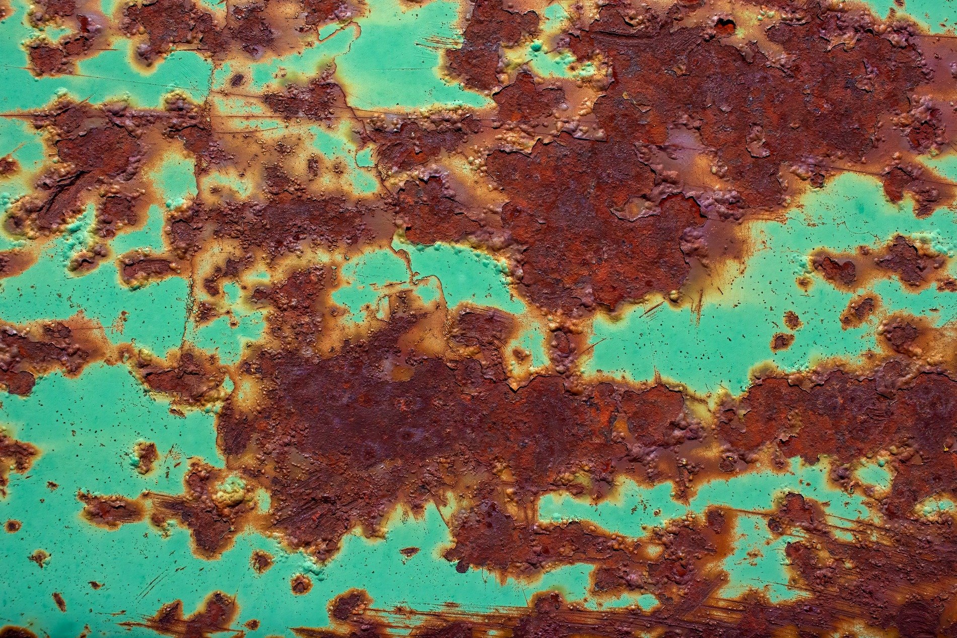 Green paint curls and peels, reddish rust spreads like a map, metal turns to dust
