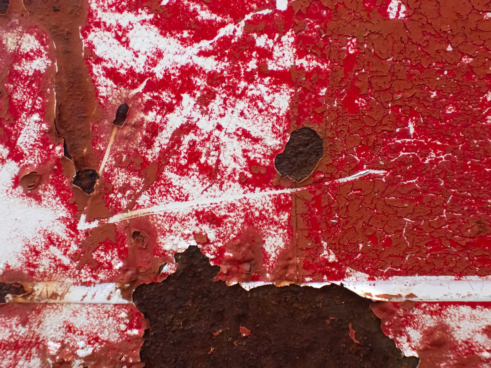 Red flakes peel away, rusted iron hides beneath, scars of passing time