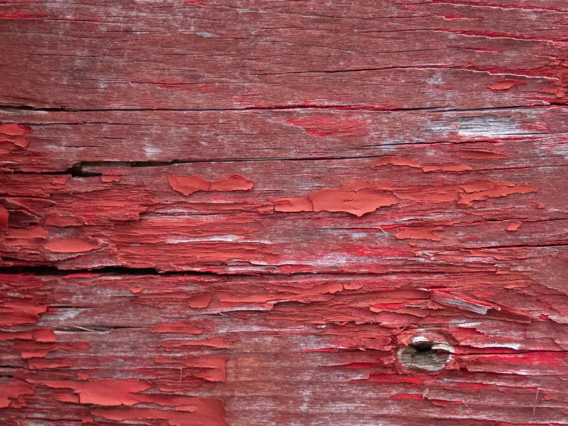 Red flakes curl and fall, weathered wood shows age through cracks, time strips bare the board