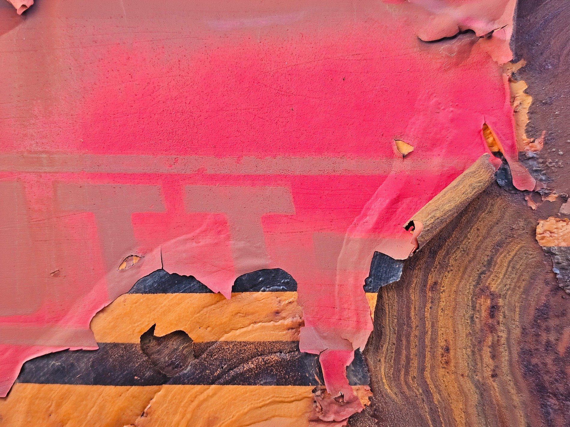 Red paint curls away, yellow stripes hidden beneath, rust claims the metal