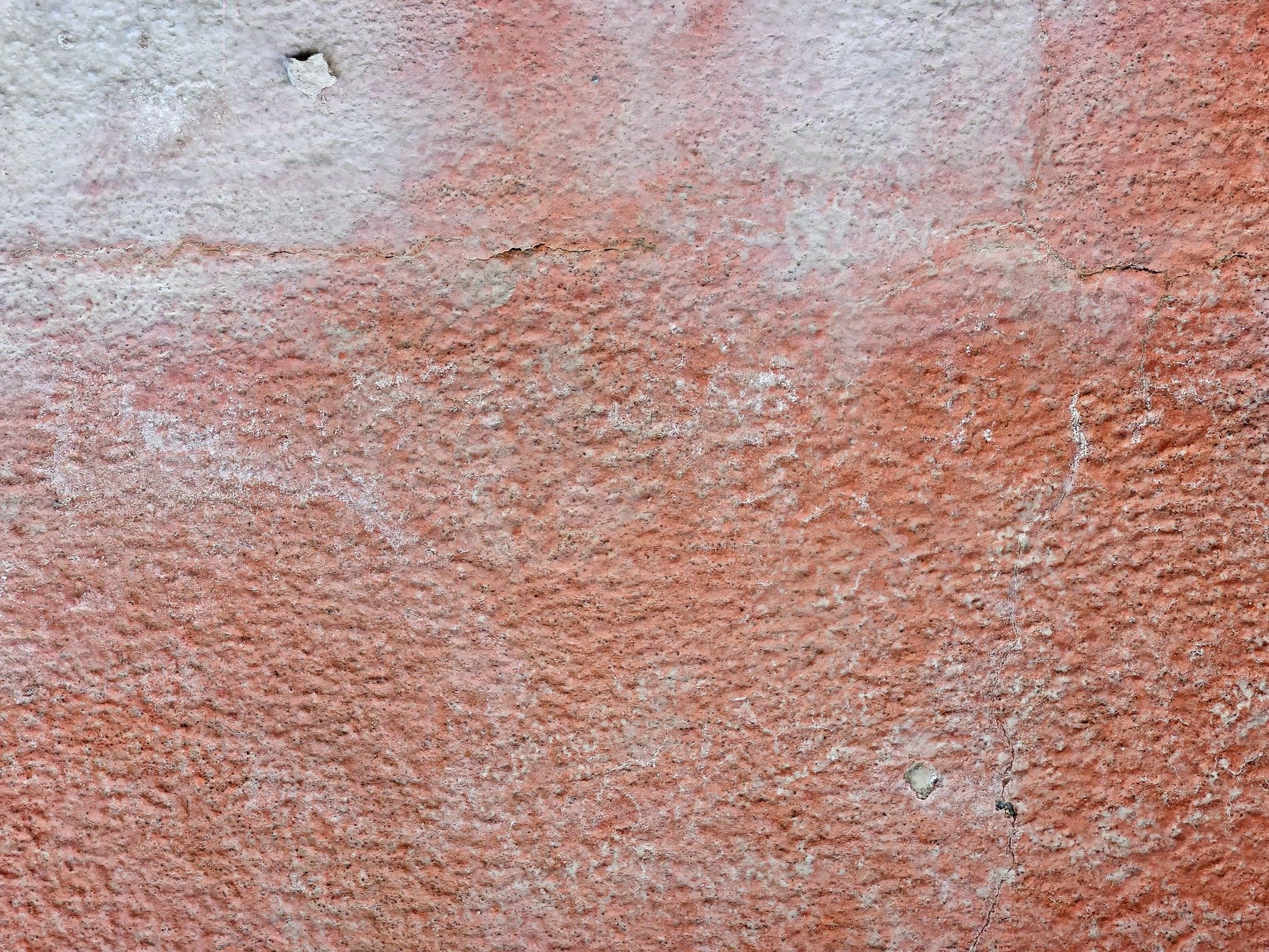 Red paint fades away, rough concrete shows through the skin, cracks trace weary lines