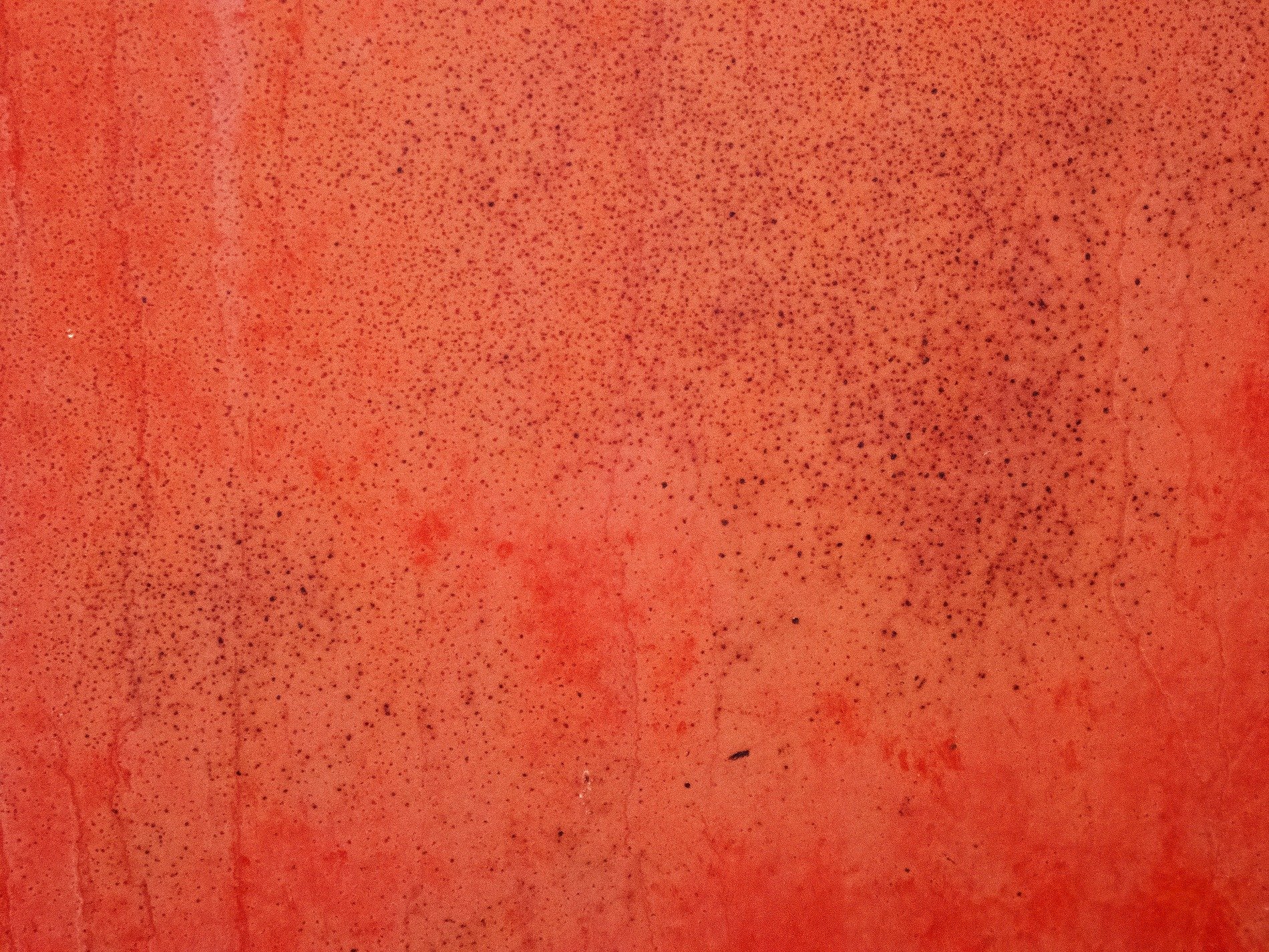 Red paint starts to fade, dark spots cover the surface, tiny cracks emerge