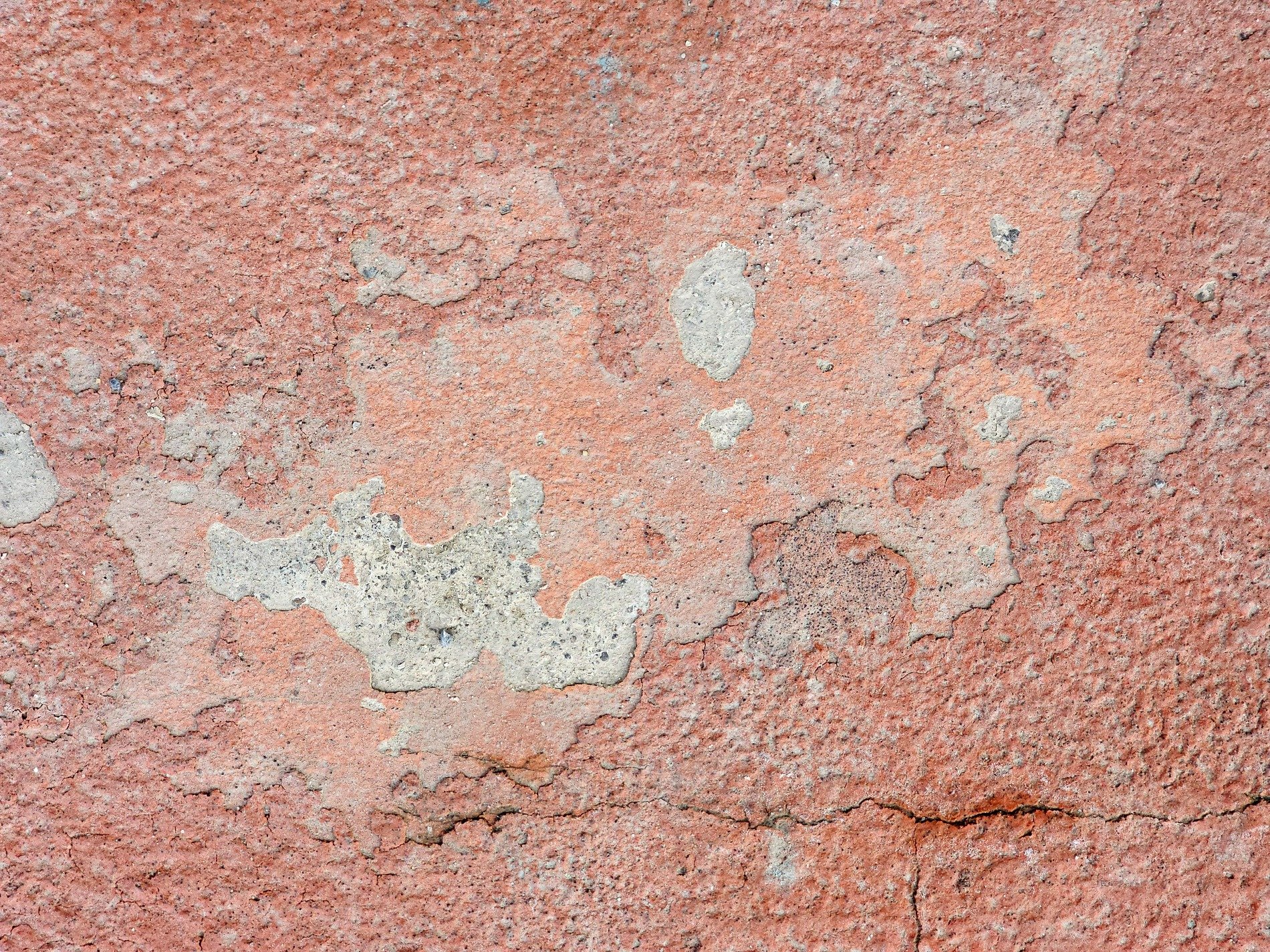 Red paint wears away, grey concrete shows through the cracks, rough textures remain
