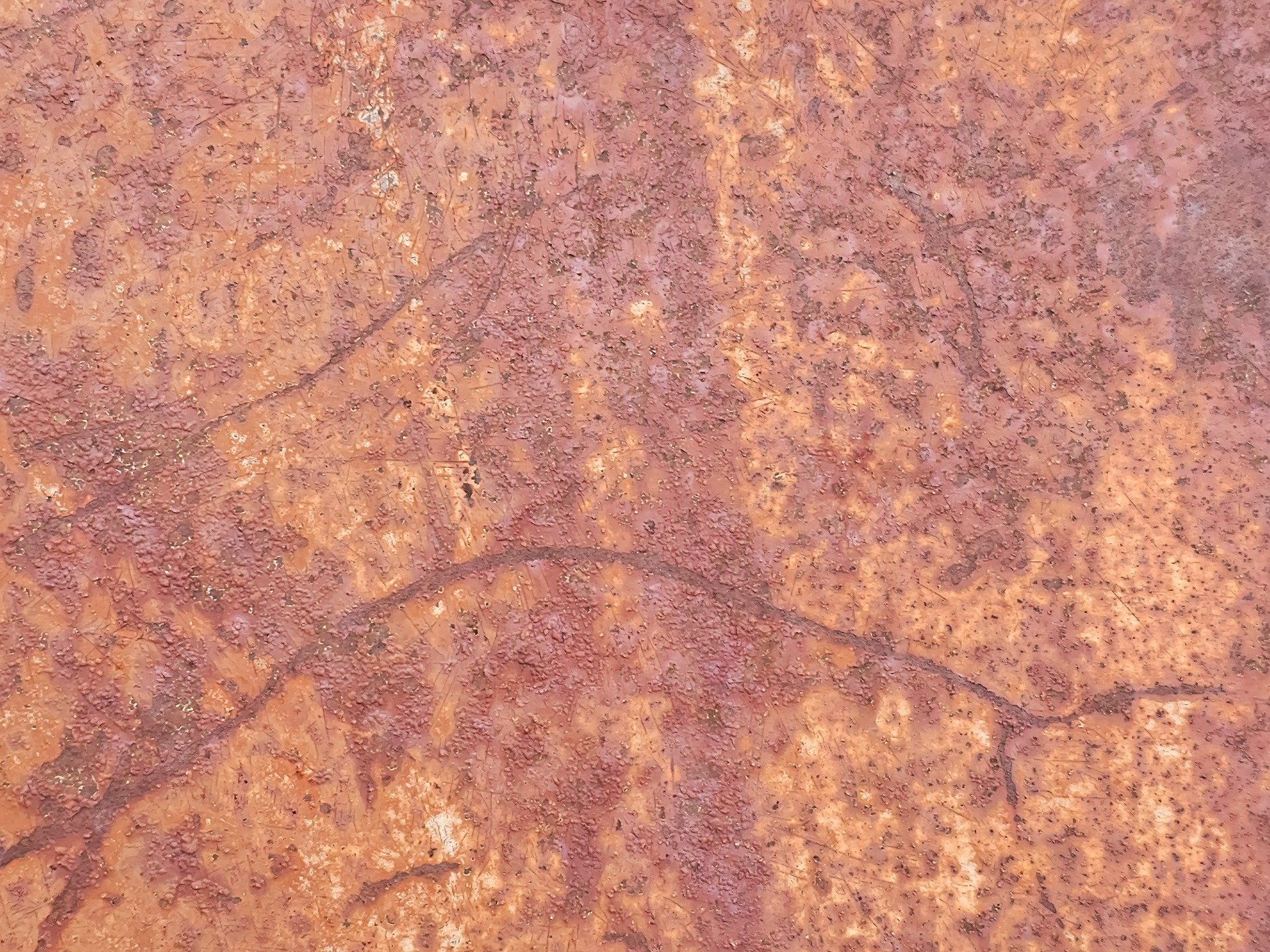 Red rust eats the steel, ancient patterns etched in time, metal yields to air