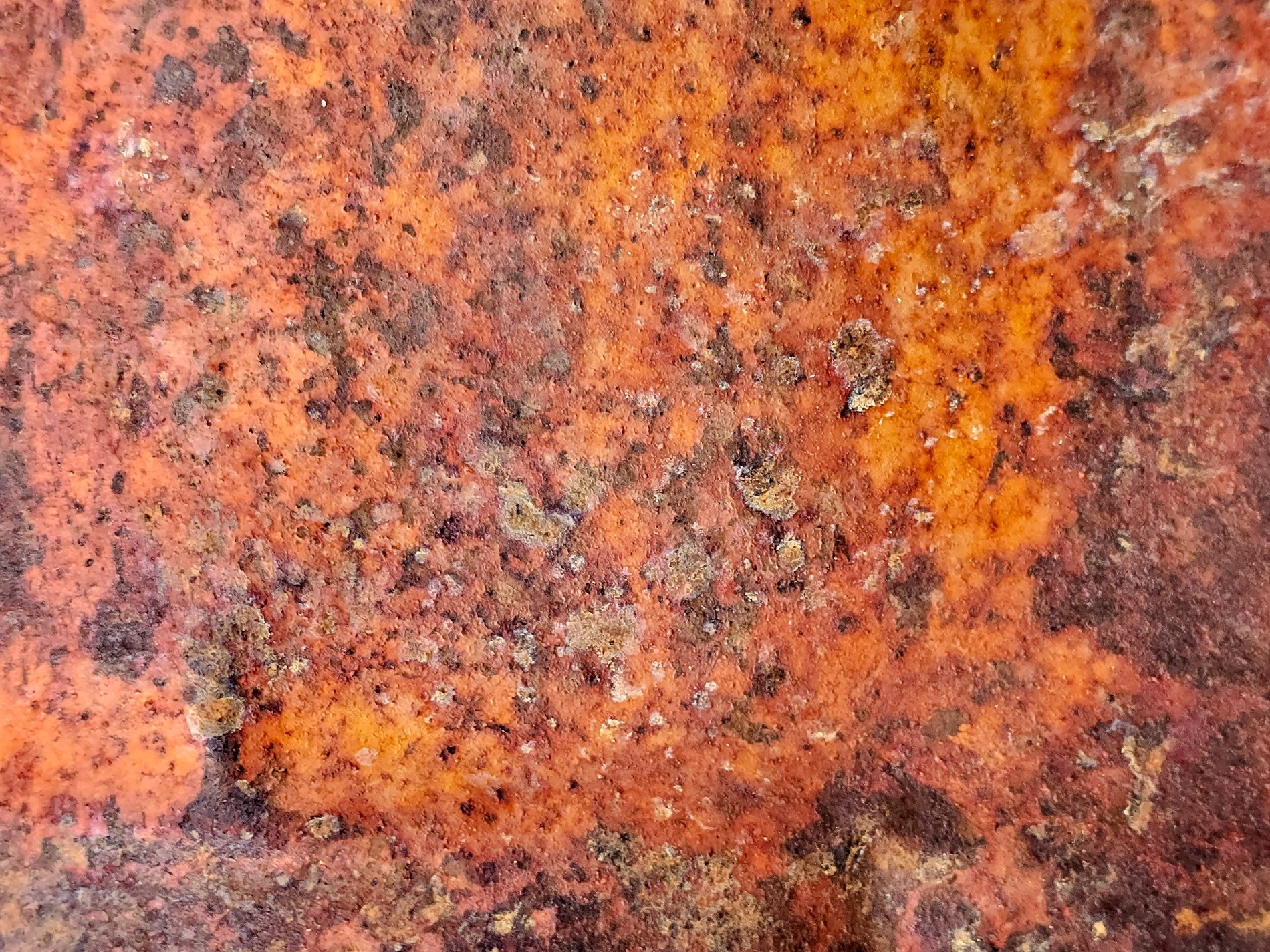 Orange rust takes hold, iron bleeds across the plate, decay eats the steel