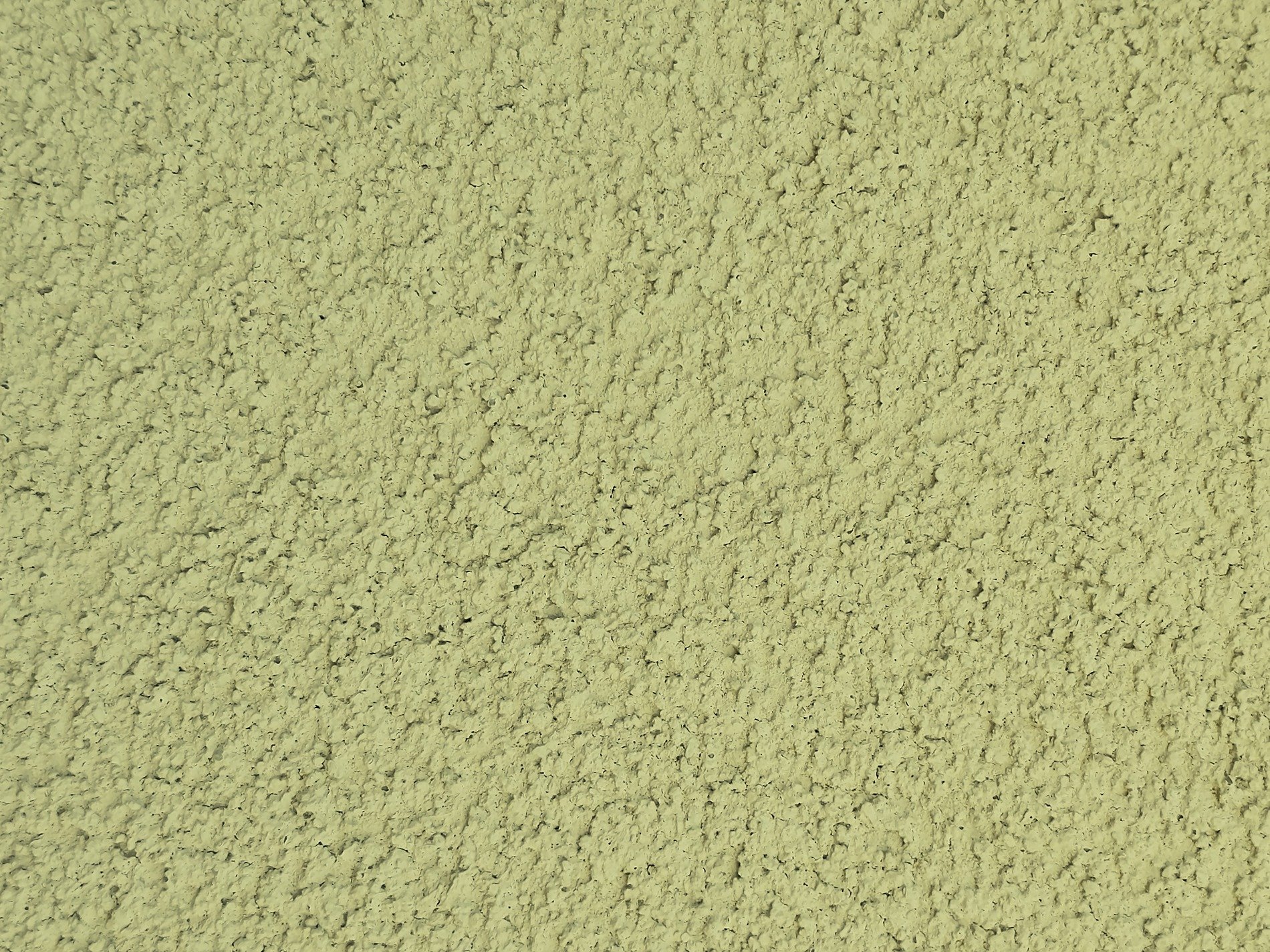 Rough green stucco wall, shadows dance on bumpy grit, uniform landscape
