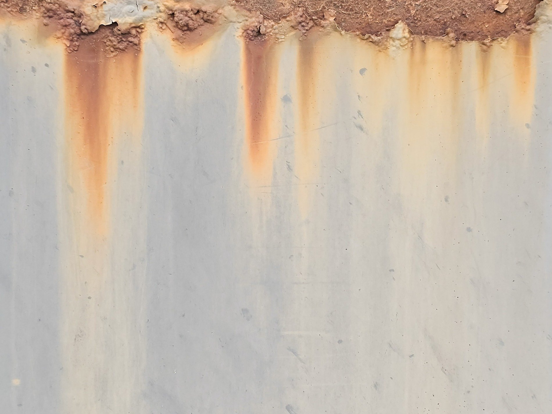 Rust bleeds from the top, orange streaks stain the gray paint, metal starts to age