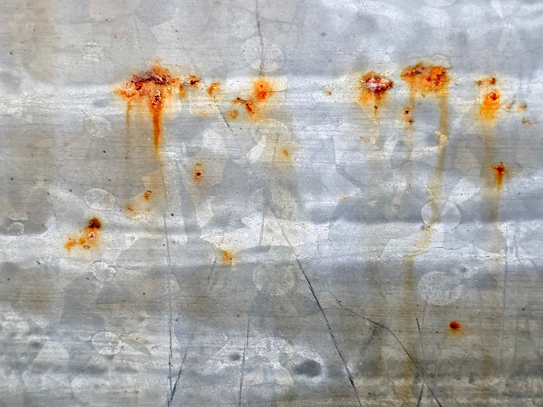 Rust blooms on the grey, orange streaks drip down the steel, metal starts to age