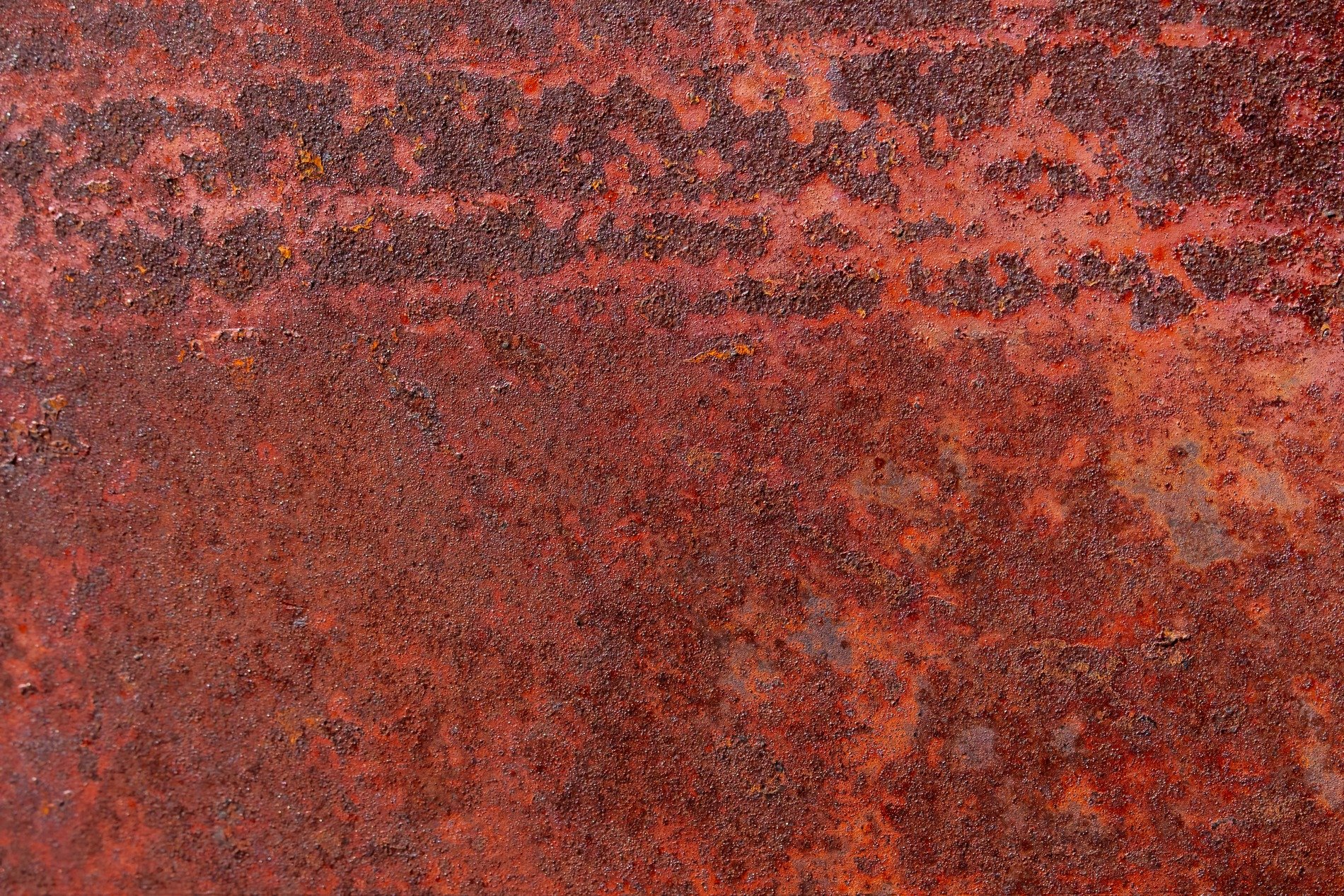 Crimson oxide blooms, rough decay on heavy steel, time consumes the plate