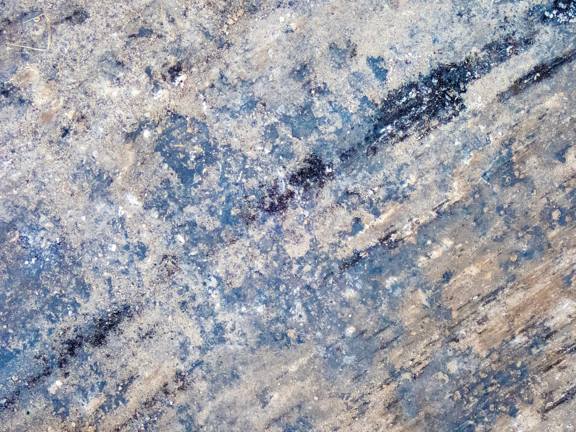 Stains of blue and grey, weathered ground holds dusty grit, rough paths mark the way