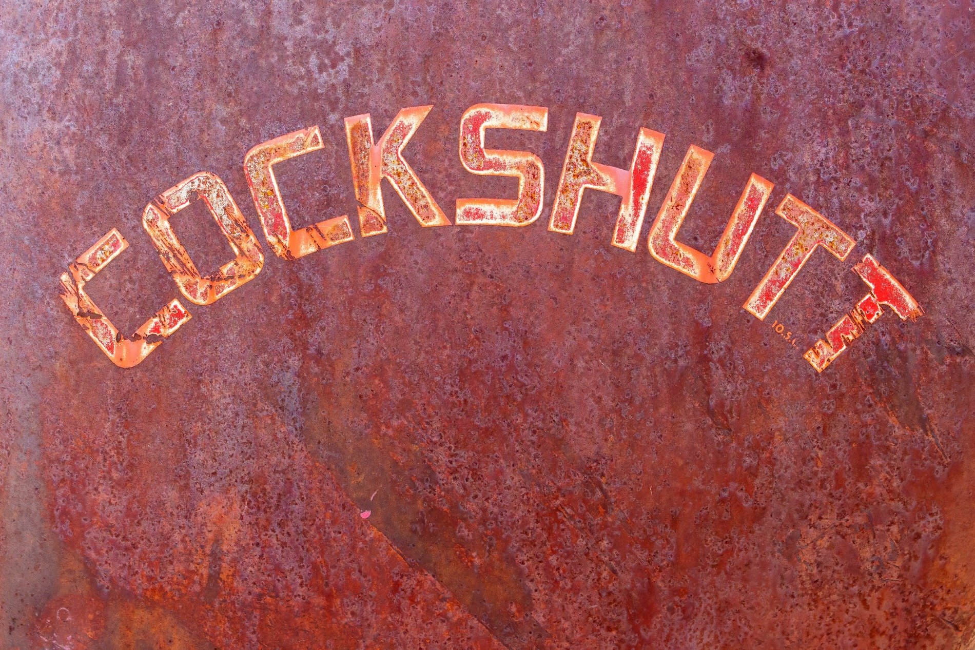 Stenciled black on rust, jagged paths trace the metal, time claims the message