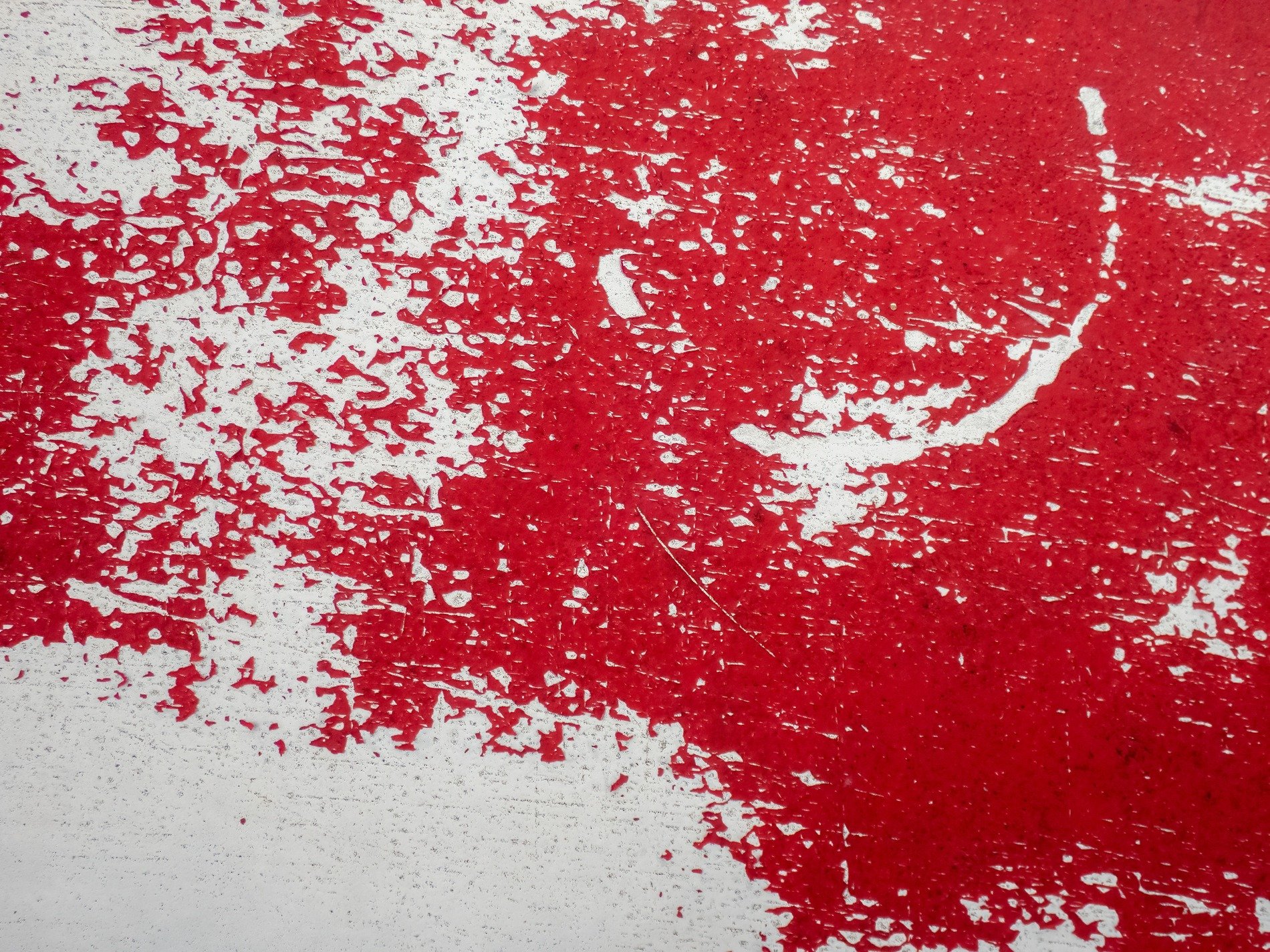 Red flakes peel away, white base breaks the crimson tide, weathered skin shows wear