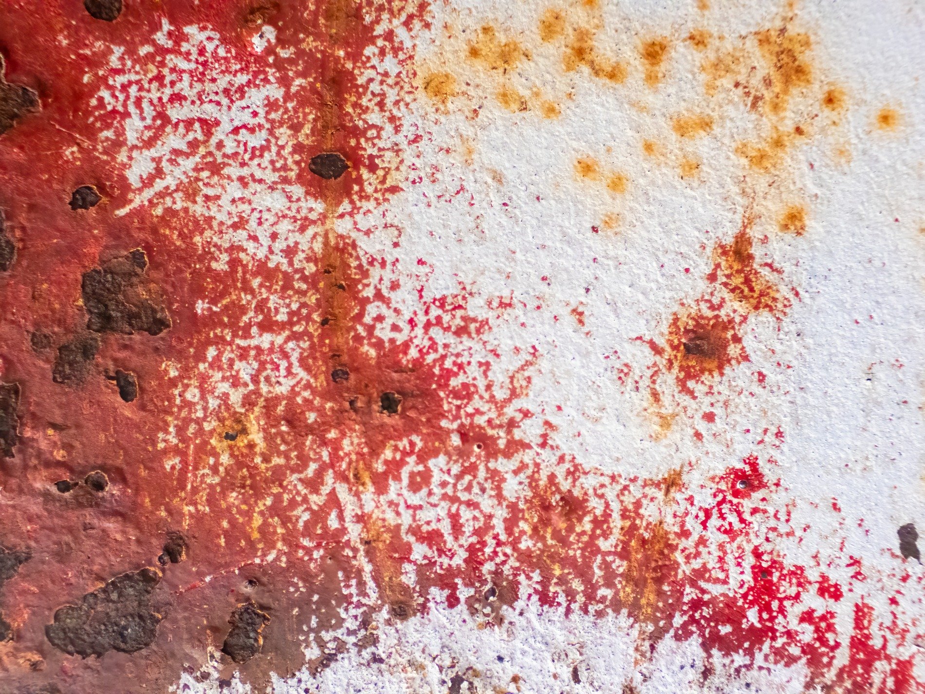 Red paint bleeds away, rust pits mark the metal skin, white gives way to age