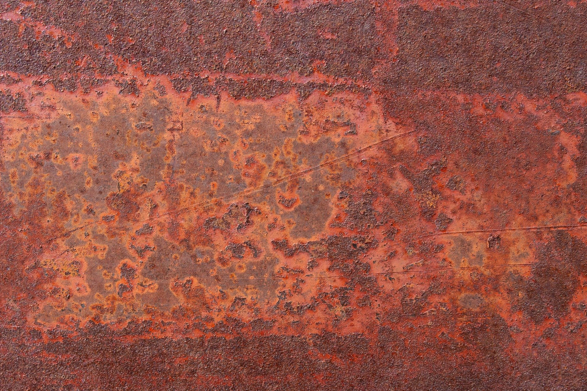 Thick rust eats the steel, orange dust coats the surface, metal flakes away