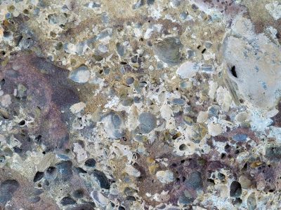 Ancient pitted stone, purple minerals bleed through, weathered grey surface