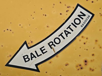 Bale rotation marks the line, yellow skin holds the warning, light carves the metal