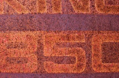 Orange oxide blooms, letters fade into the grain, iron turns to dust