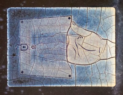 Blue hand guides the lock, cracks divide the faded sign, age patterns the film