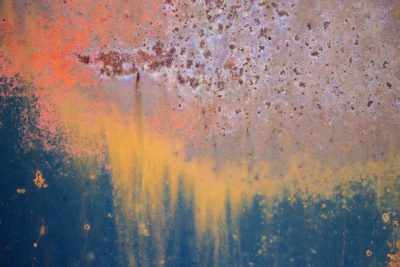 Blue mist holds the field, orange grit claims the surface, light catches the edge