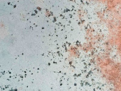 Pale blue surface fades, copper rust creeps from the edge, dark spots mark the age