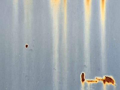 Blue paint fades away, orange rust bleeds through the steel, marks of time remain
