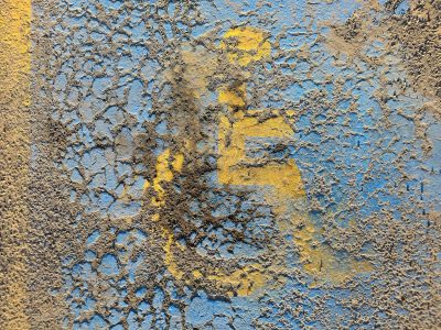 Blue paint peels away, yellow symbol starts to fade, cracks web through the ground