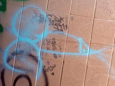 Blue paint spans the tile, scribbled words hide in the grit, stone wears every mark