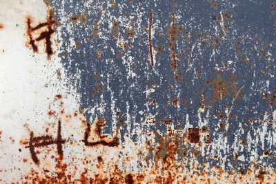 Blue paint wears away, orange rust bleeds through the skin, etched marks tell the tale