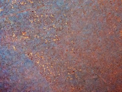 Deep blue metal fades, orange rust blooms like embers, time consumes the steel