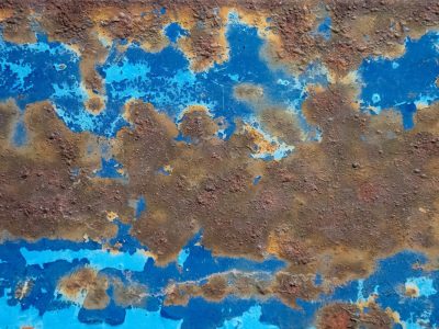 Blue paint flakes away, rusted iron breathes the air, decay paints the steel