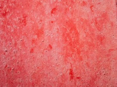 Crimson stains the stone, pitted surface holds the hue, layers wear with time