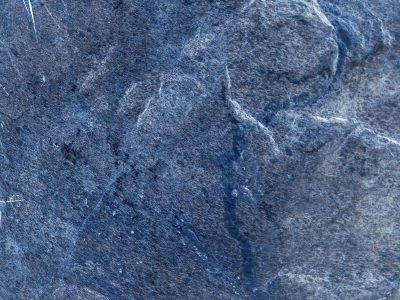 Blue stone wears its age, ridges catch the fading light, rough paths cross the face