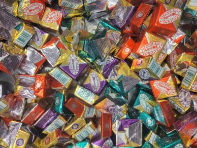 Bright foils wrap the treats, Icy Squares in tangled pile, sugar waits within