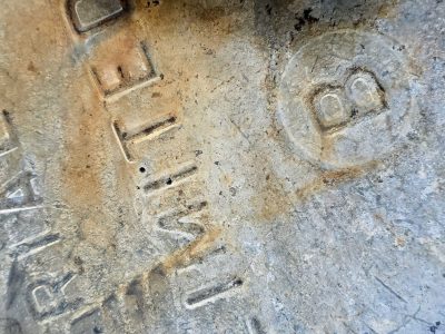 Cold iron surface, rust stains crawl across the steel, words stamped deep in time