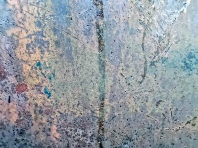 Cold steel bears the scars, blue and grey meet rust and dust, central seam holds fast