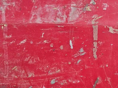Crimson paint is scarred, white marks dance on worn surface, rough story unfolds