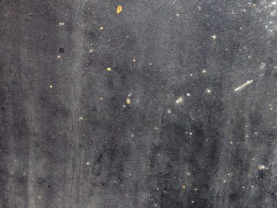 Dark void wears its scars, orange sparks in endless gray, dust clouds hold the light