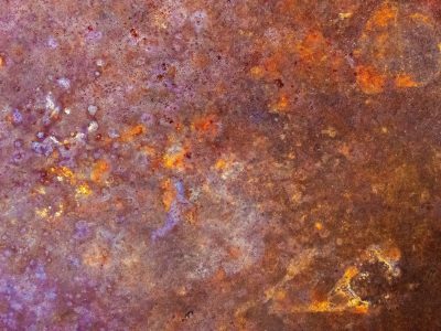 Deep iron decays, orange blooms on purple steel, oxidation glows