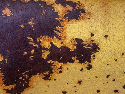 Gold mist holds the field, dark trails trace the heavy skin, light carves the metal