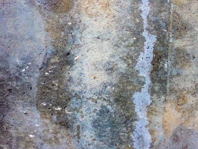 Gray stone holds the stain, blue trails mark the weathered wall, time wears down the stone