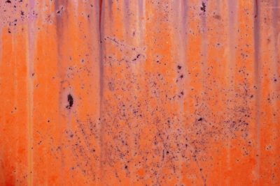 Bright orange metal, purple streaks flow down the side, rust blooms in the heat