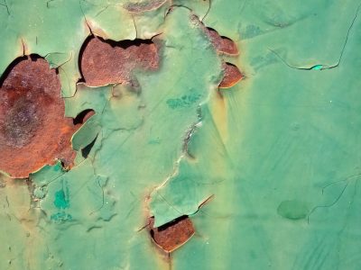 Green paint curls away, iron rust bleeds from within, time peels back the skin